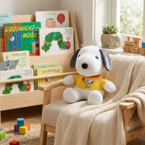 Snoopy plush in a yellow shirt sitting on a child's armchair.